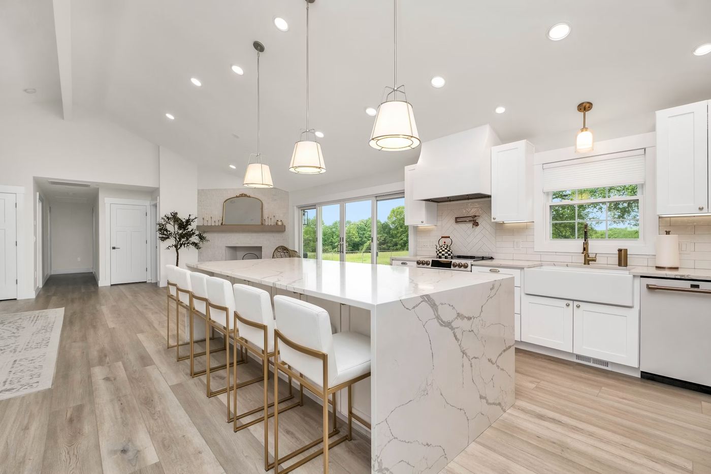 A large white kitchen with a long island and four counter stools
